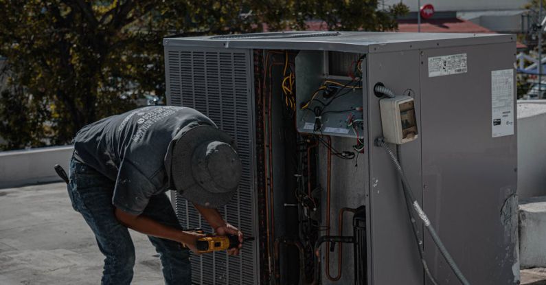 Air Conditioner - Man Drilling an Aircon Casing