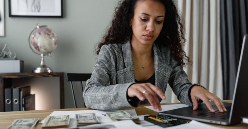 AC Budget - A Woman in Plaid Blazer Using Her Laptop and Mobile Phone