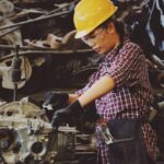 AC Maintenance - Woman Wears Yellow Hard Hat Holding Vehicle Part