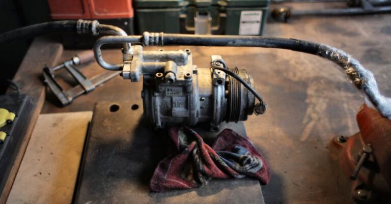 AC Compressor - From above of rusty metal detail with pipes placed on grungy table in old fashioned workshop