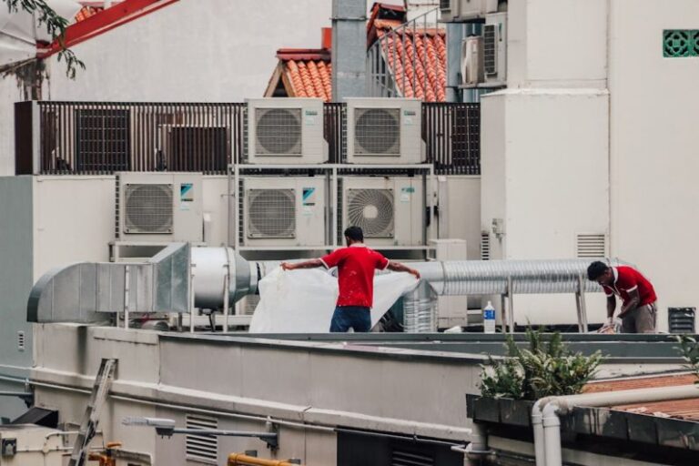 Air Conditioner - a couple of men standing on top of a roof